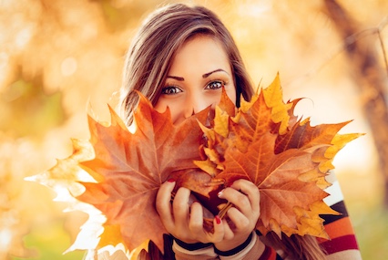 Frau mit bunten herbstblättern sinnbildlich für Microneedling im Herbst