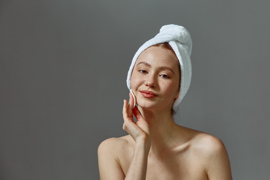 Junge Frau bei Gesichtsreinigung entfernt Make-up mit einem Wattepad mit Mizellenwasser